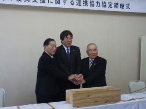手を取り合う（左から）秋元代表理事会長、後藤常務理事、齋藤会長